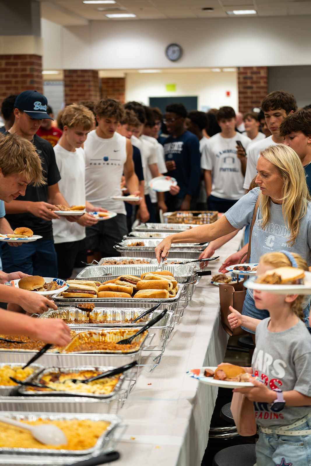 Players and families filling plates along the buffet line at the Cambridge Bears team dinner