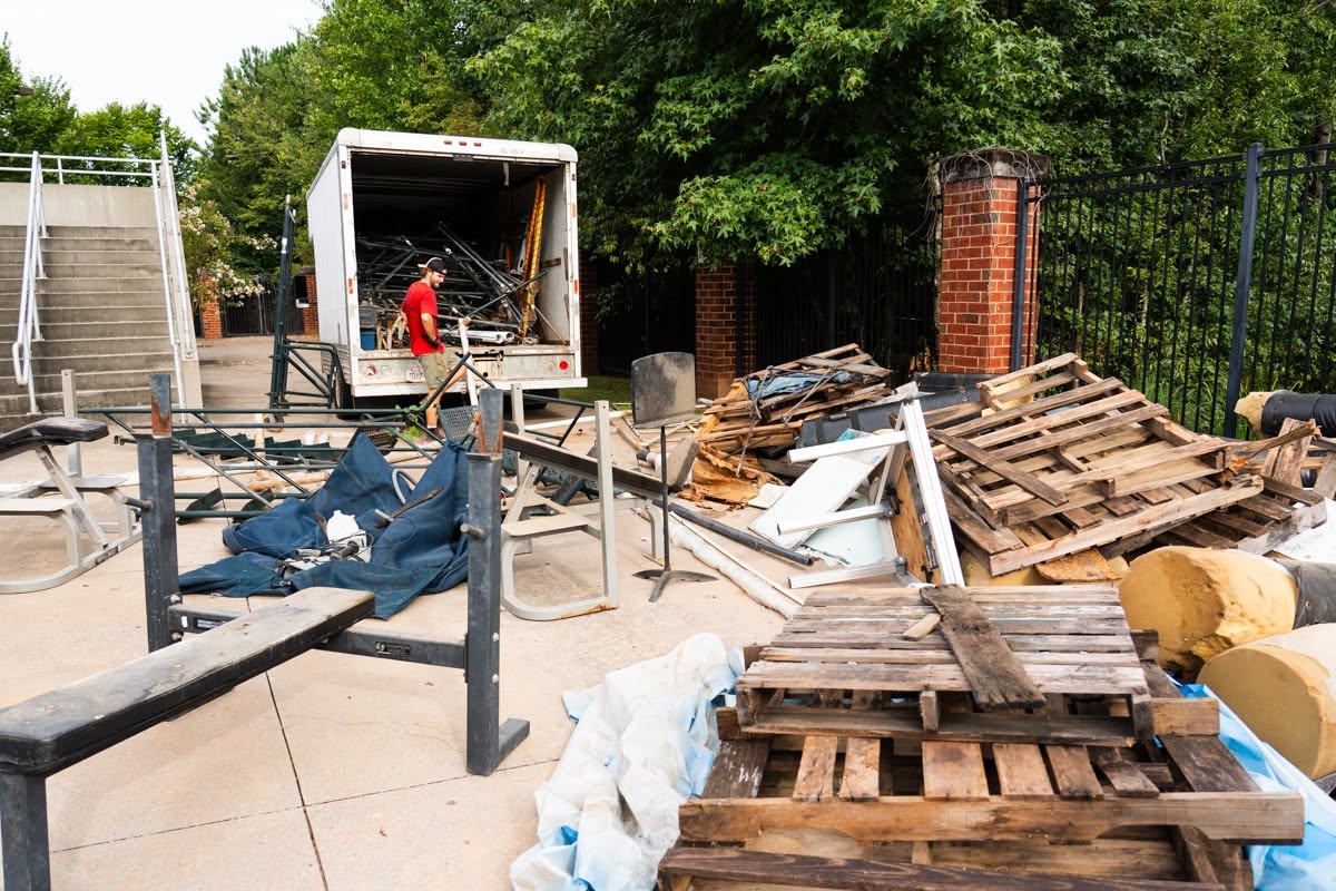 Truckload of old equipment and trash being loaded into a box truck outside the stadium during the Bear Gridiron Club work day
