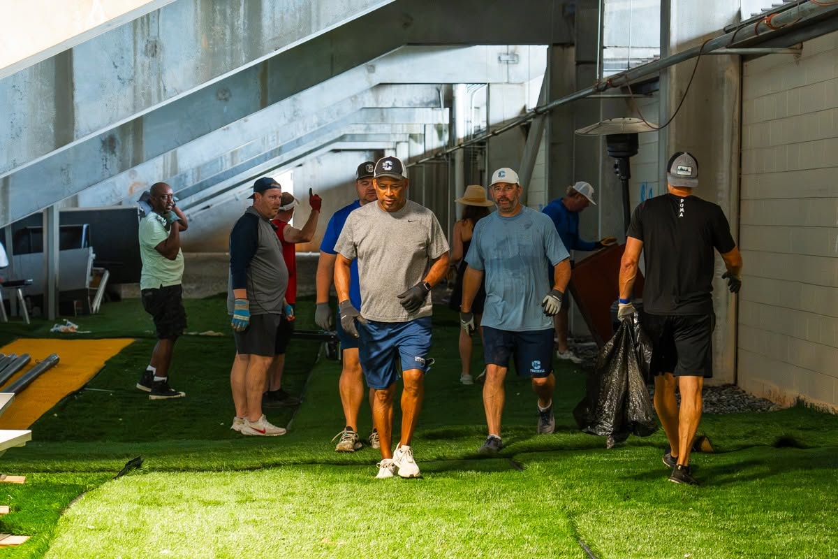 Bear Gridiron Club volunteers working together in the Bear Cave under the stadium bleachers on the new turf